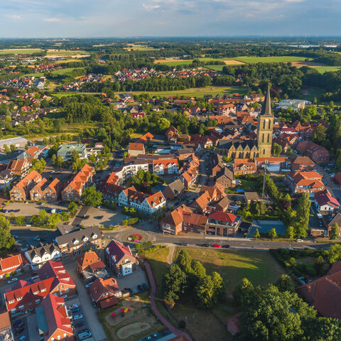 Luftbild vom Ortskern Emsbüren, Häuser mit roten Dächern und der Kirchturm der St. Andreas Kirche.